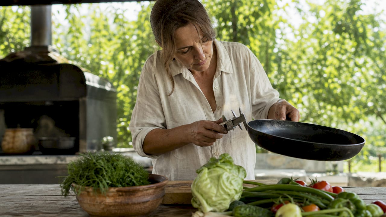 Woman measuring carbon steel pan thickness in kitchen